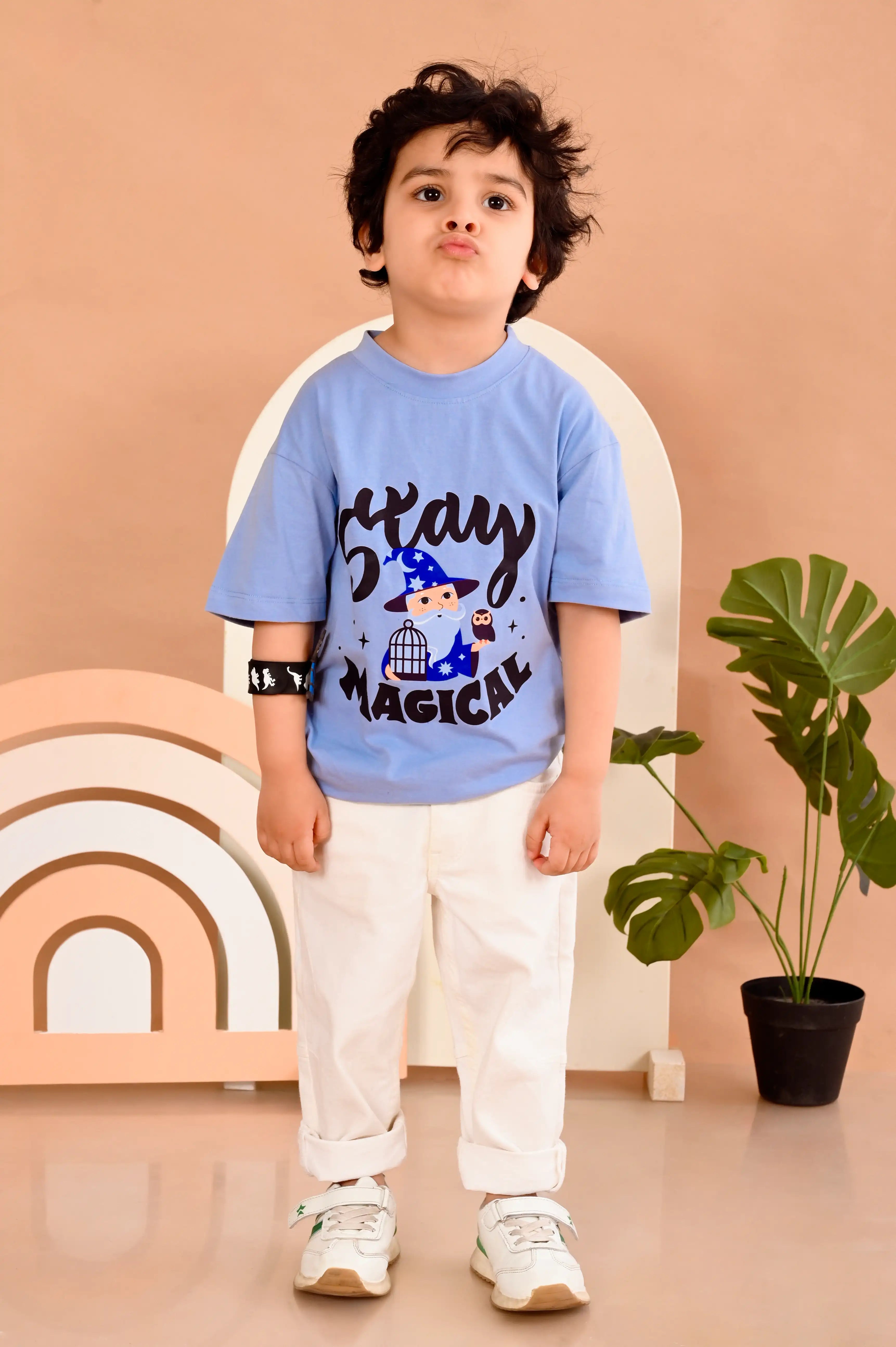 Child wearing an ash blue round neck t-shirt with stay magical text and graphics made out of pure cotton .